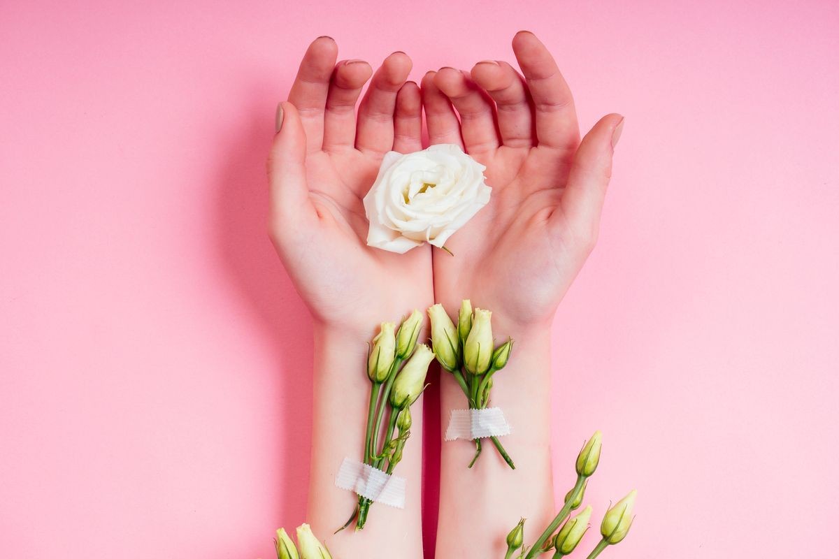 Nude manicure.Natural freshness and youth girl hands ,hand cosmetics with white rose flower adhesive plaster .Fashion woman hand with flowers and leaves,herbal skin care pink background studio shot